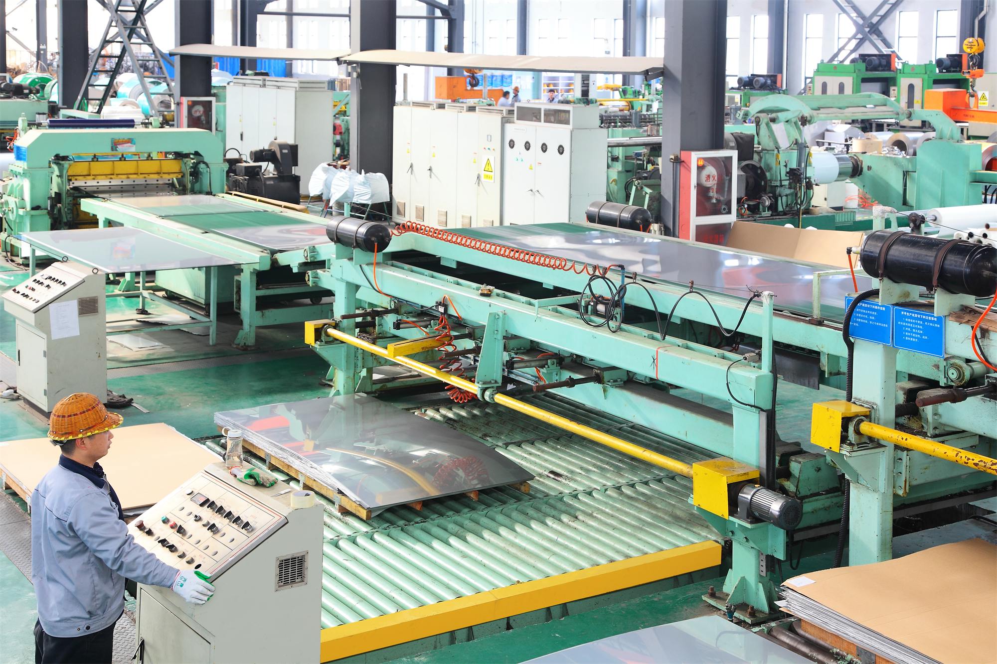A stainless steel sheet being cut to length, the step that fixes panel size before a printed graphic is positioned
