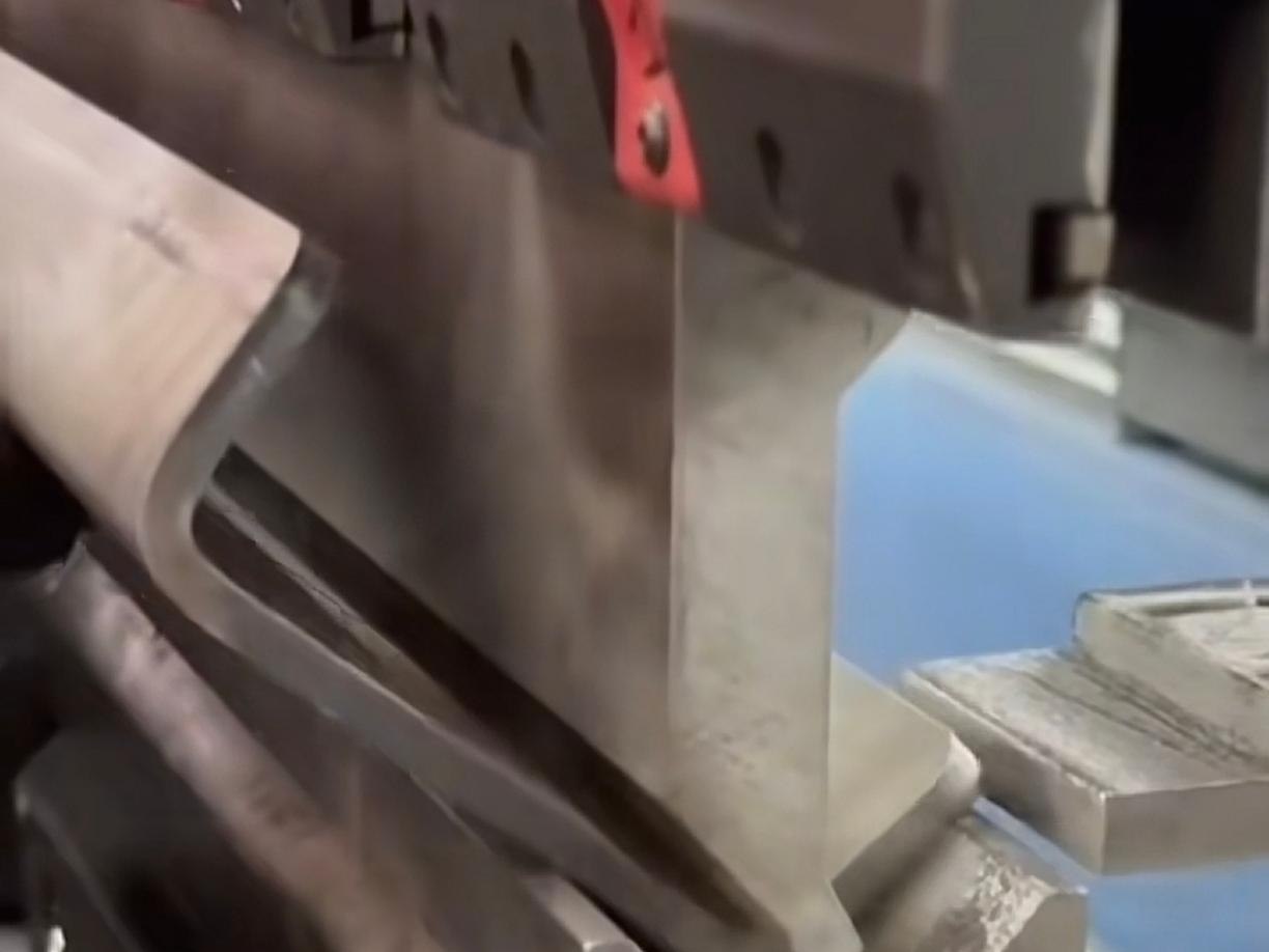 A printed stainless steel panel being formed, where the graphic is checked across folds and visible returns
