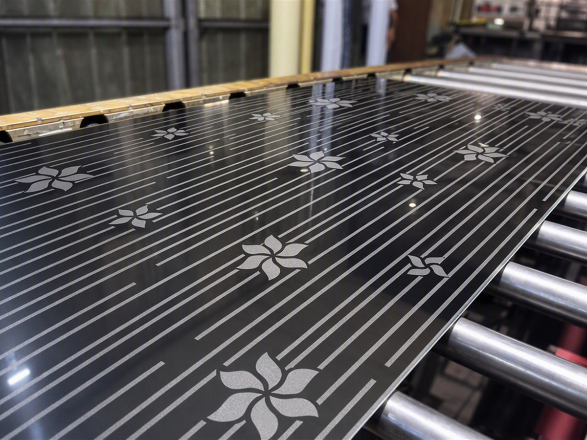 An etched stainless steel sheet carrying the approved pinwheel pattern on the production line, produced as a finished architectural panel