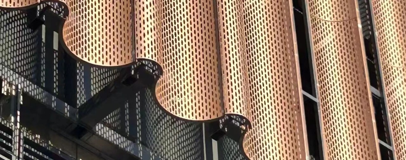 Copper-colored PVD perforated stainless steel illuminated by daylight