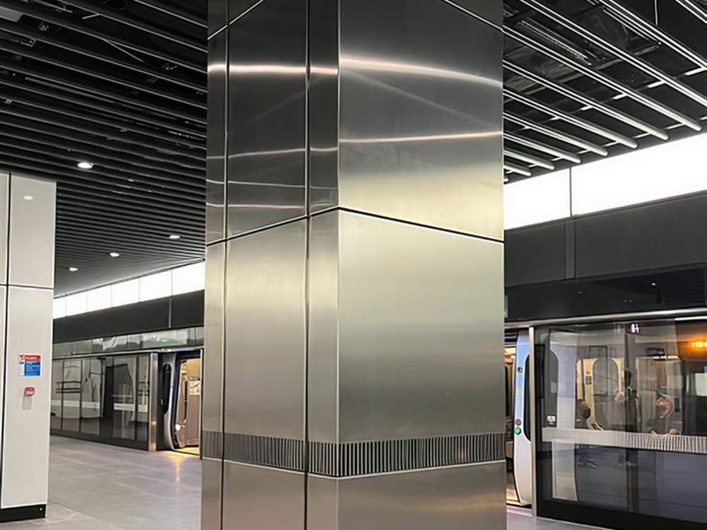 An untreated brushed stainless steel column showing visible finger marks and touch smudges under directional lighting