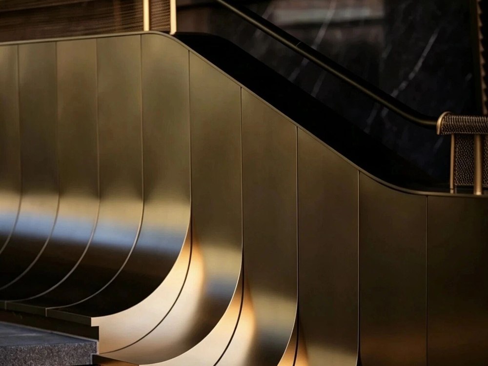 A gold PVD coated stainless steel stair balustrade with a brushed handrail in a hotel lobby