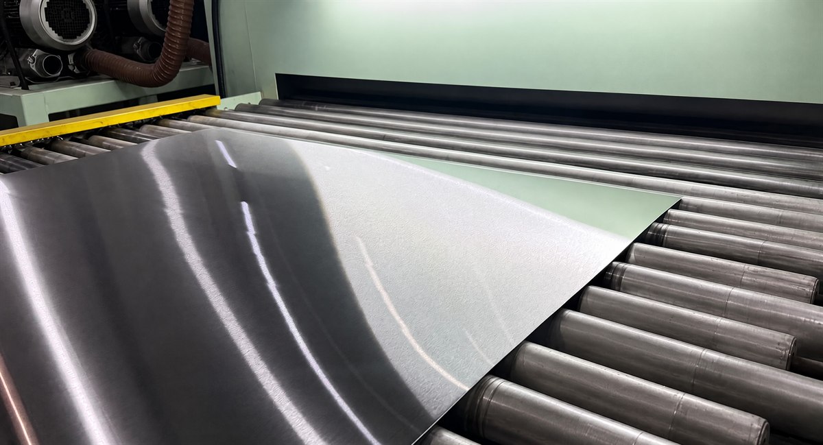 Sheet-to-sheet grinding line finishing a brushed stainless steel sheet on a roller table