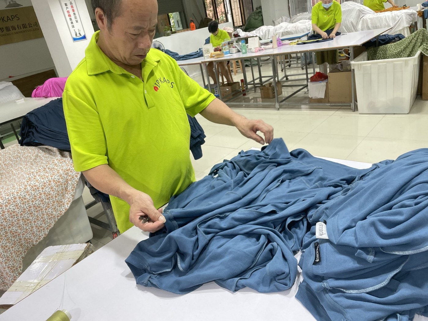 Quality inspector checking blue knit sleepwear fabric before packing at a Chinese pajama factory