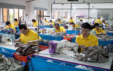 Pajama factory production line with operators sewing sleepwear garments at industrial sewing machines