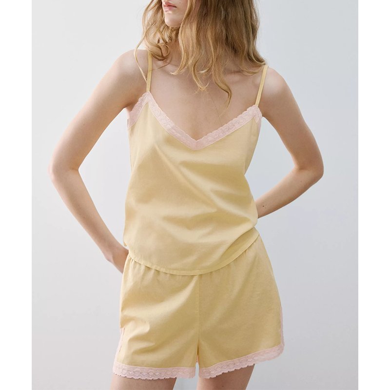Close view of the scalloped lace V-neckline and lace-trimmed shorts of the yellow satin cami pajama set