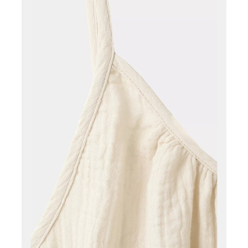 Close view of the gathered cotton gauze neckline and slim strap on a cream cami nightgown
