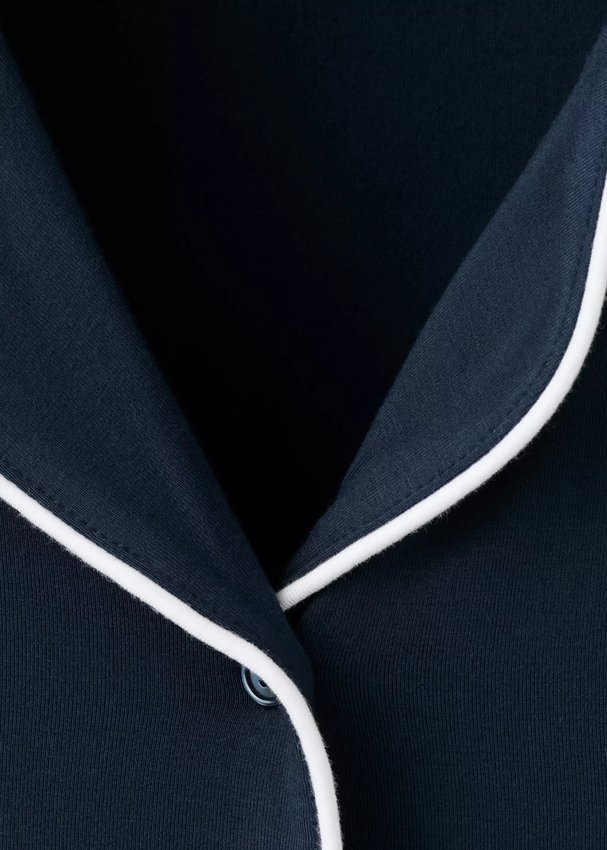 Close view of the white contrast piping on the notch collar and button placket of a navy modal knit pajama set