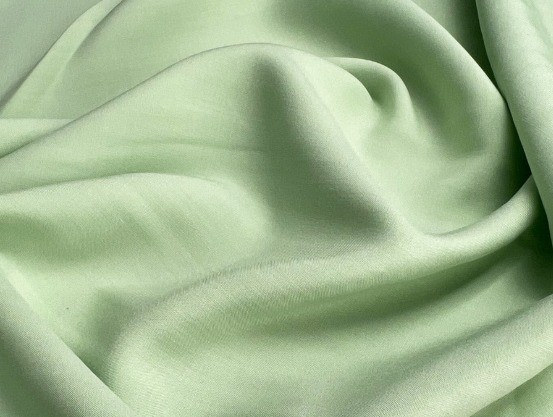 Pale green viscose fabric with a soft, fluid drape and smooth folds