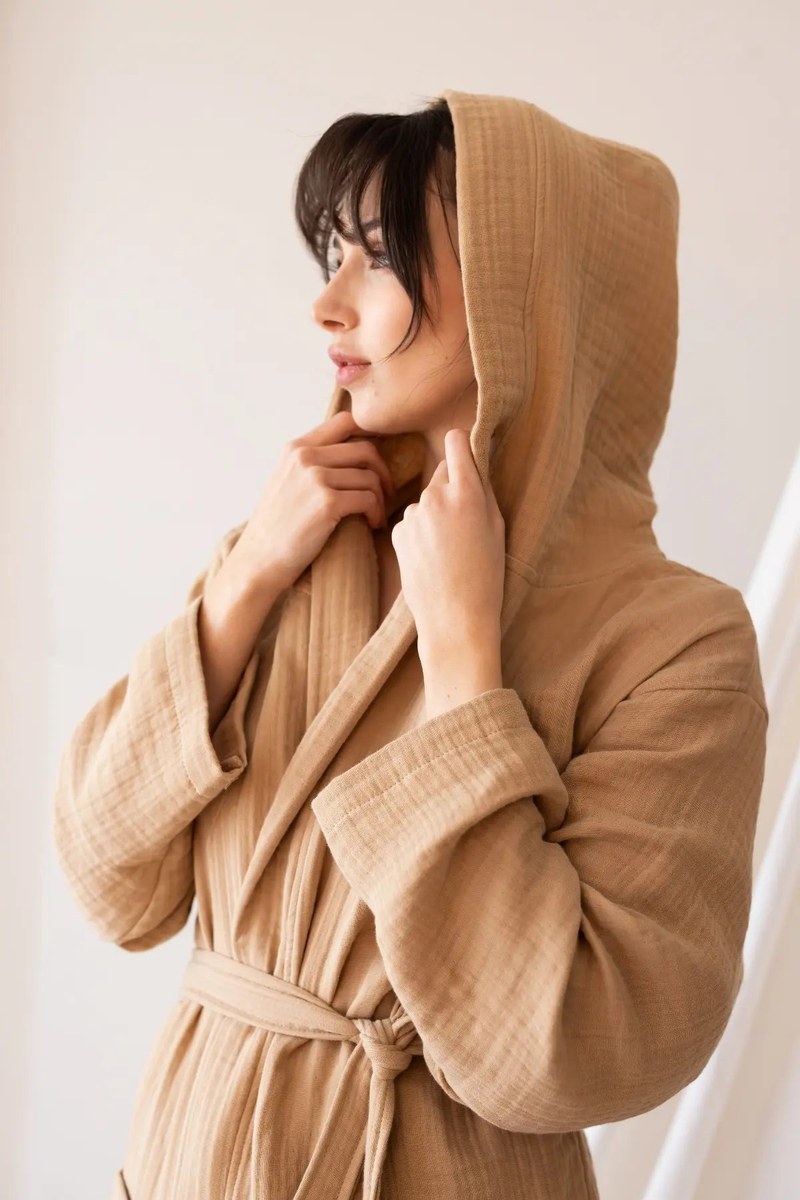 Tan waffle-weave hooded robe with the hood worn up and a knotted tie belt