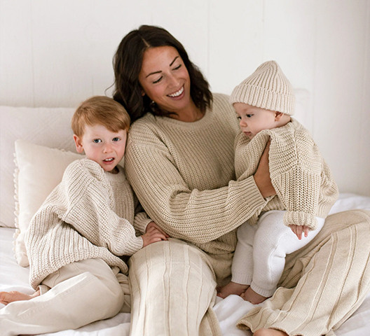 Mother and two children wearing cream chunky knit sweaters from a custom sweater manufacturer