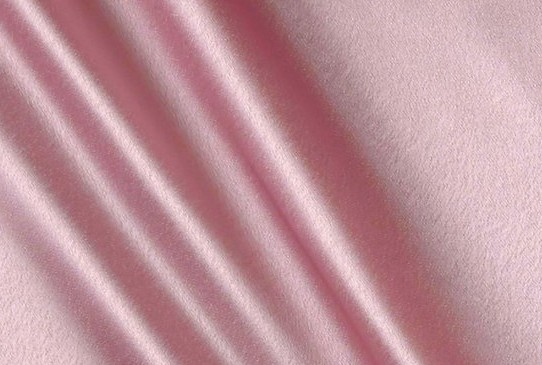 Soft pink satin fabric with a glossy face and fluid diagonal folds catching the light