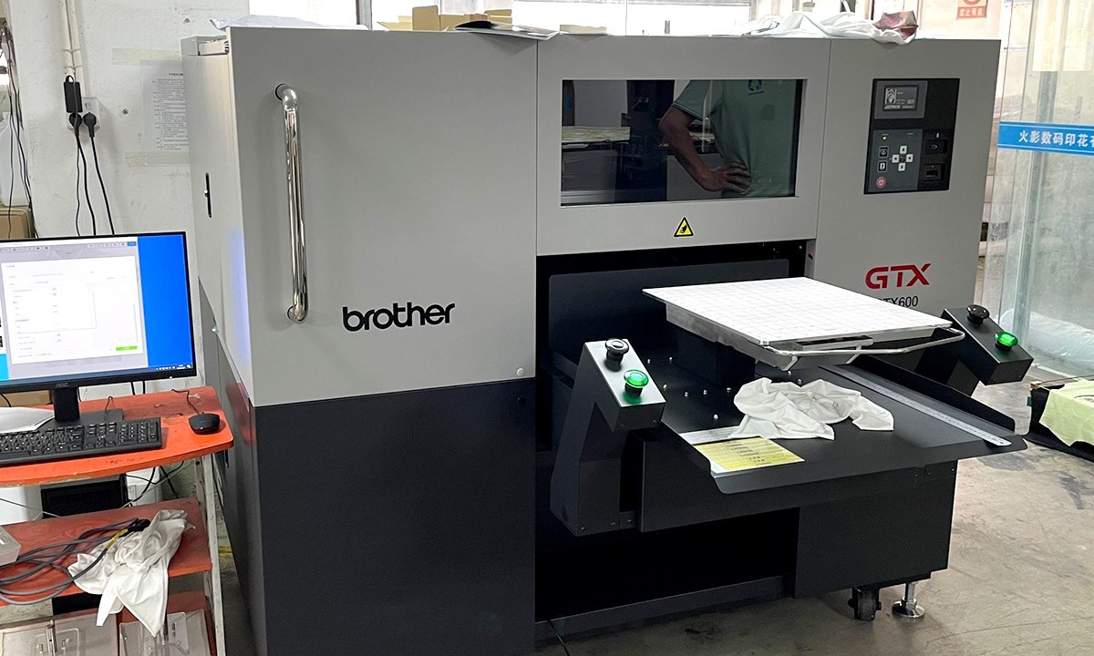 Brother GTX direct-to-garment printer printing a white pajama panel in a fabric printing workshop