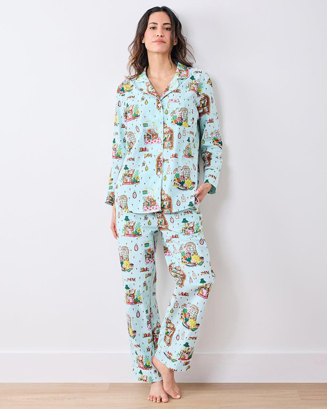 Woman wearing a mint green pajama set covered in an all-over Christmas illustration print