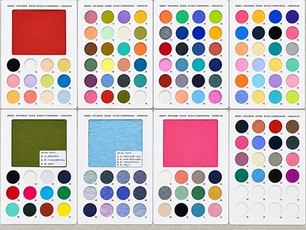 Fabric swatch book open to pages of red, green, blue and pink fabrics with matching colour chips