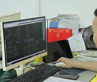 Pattern maker working at a computer screen showing digital pajama pattern pieces in CAD software