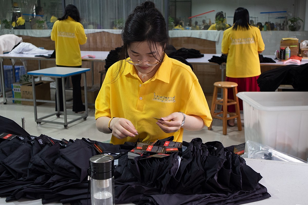 Finishing worker attaching brand hangtags to finished garments before packing