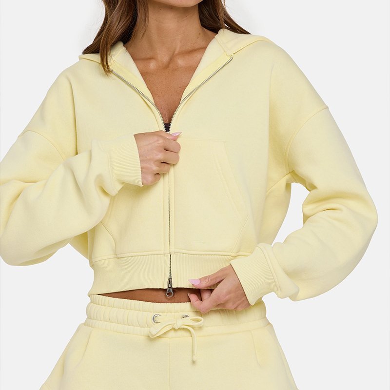 Close-up of the cropped hem and metal zip on a buttercream fleece hoodie