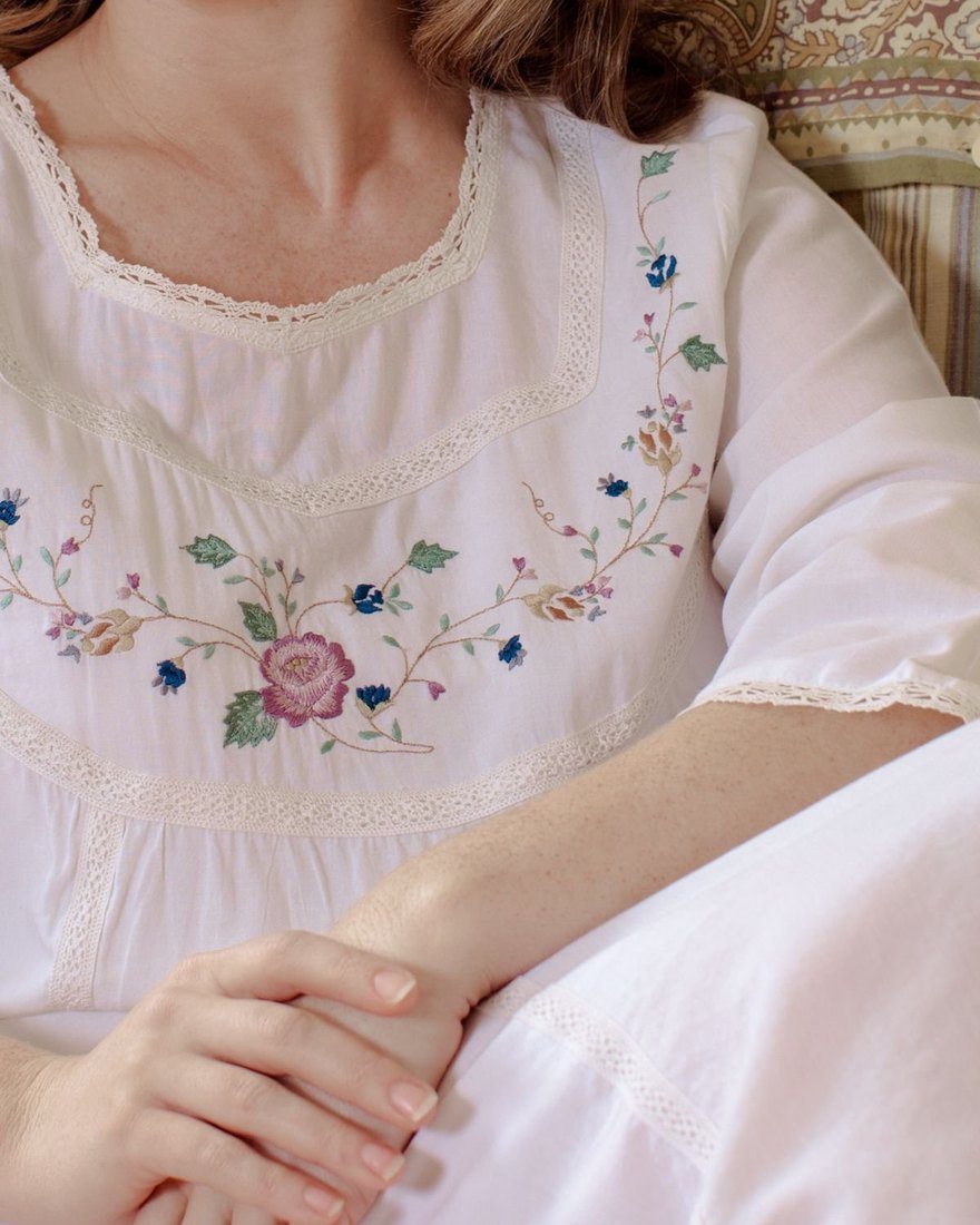Floral embroidery on the yoke of a white cotton nightgown with lace trim
