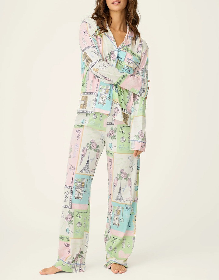 Woman wearing pastel pajamas printed with illustrated Paris scenes, buildings and floral motifs