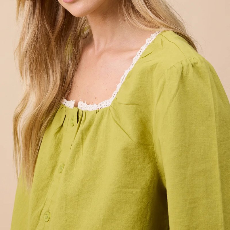 Close-up of the white lace trim on the square neckline of the cotton linen pajama top