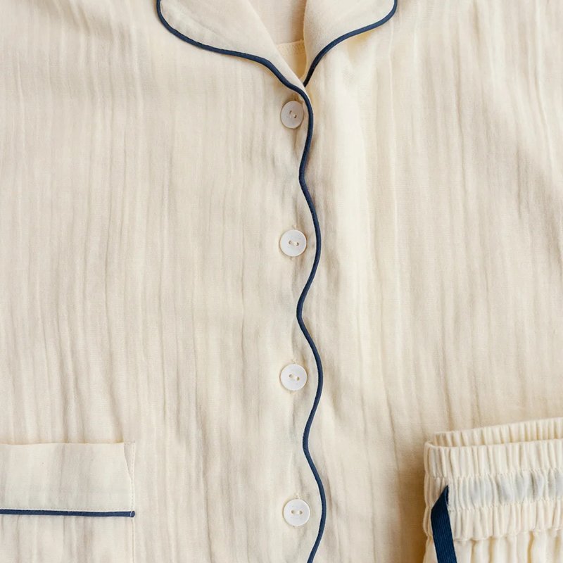 Close-up of the navy piped placket and buttons on the buttermilk cotton pajama shirt