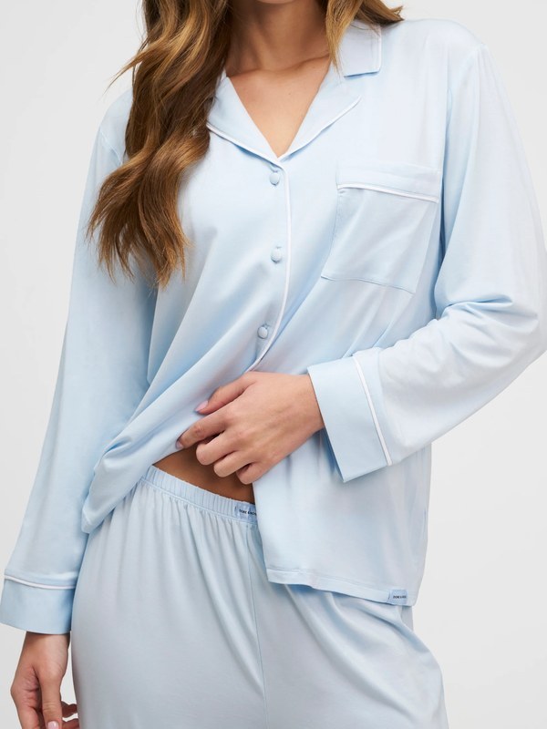 Close-up of a light blue modal pajama set showing piping, chest pocket and cuffs