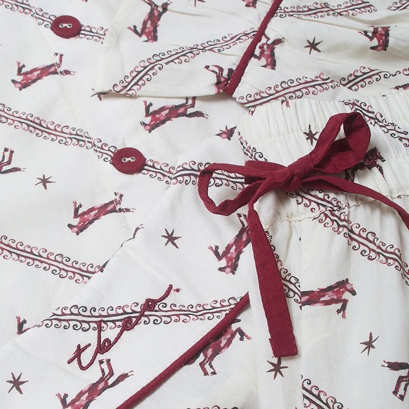 Close-up of the ribbon drawcord and horse print on the cream cotton pajama pants