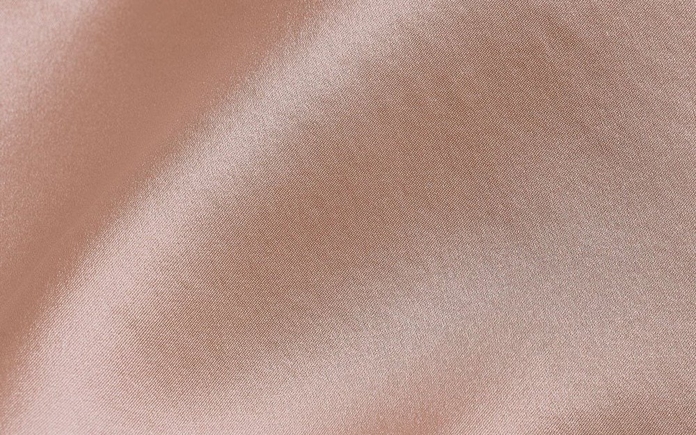 Close-up of blush silk satin fabric showing its soft lustre and fluid drape