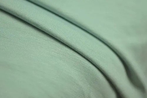 Close-up of sage green modal jersey with a fine, smooth knit surface and soft folds