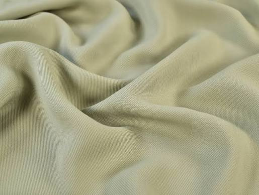 Close-up of pale khaki viscose fabric with a soft, fluid drape and fine surface texture