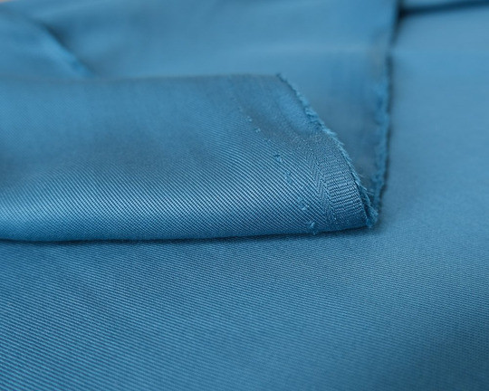 Close-up of blue lyocell fabric with a smooth surface, soft sheen and visible woven texture