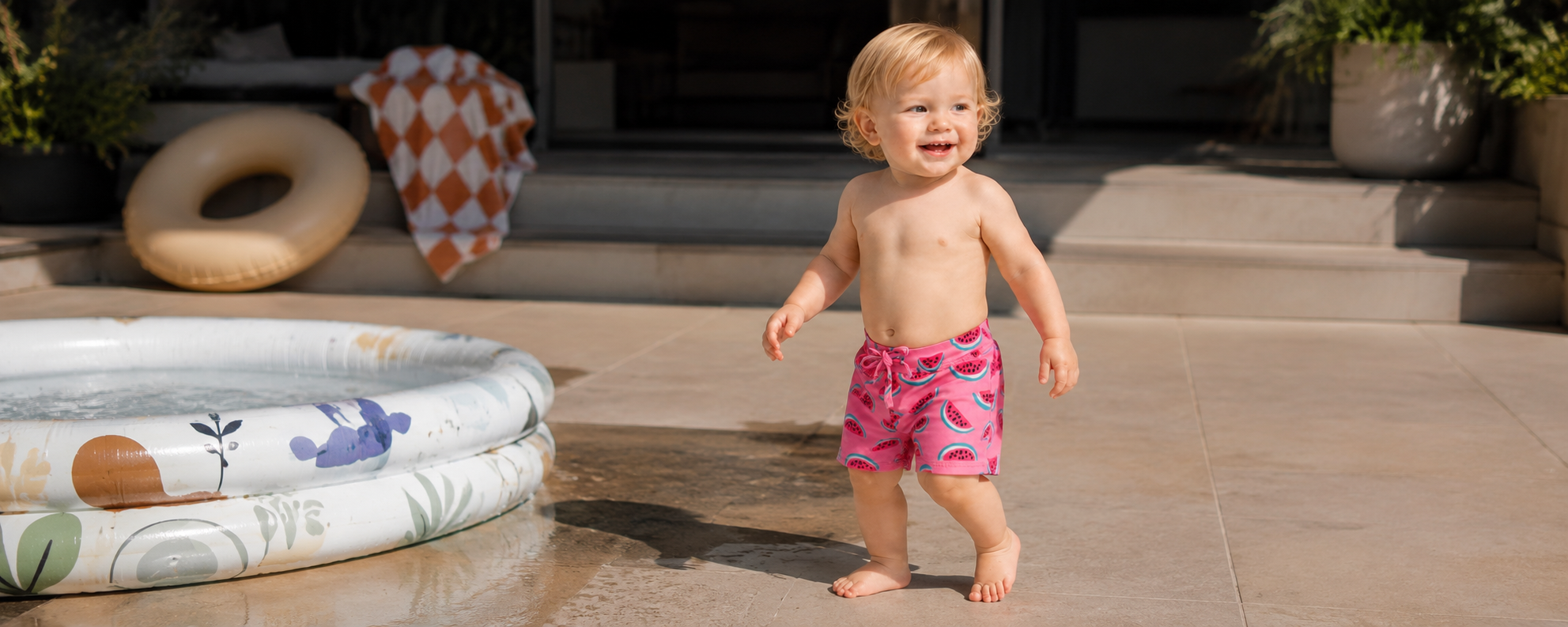 Toddler wearing pink watermelon print baby swim trunks with drawstring waist