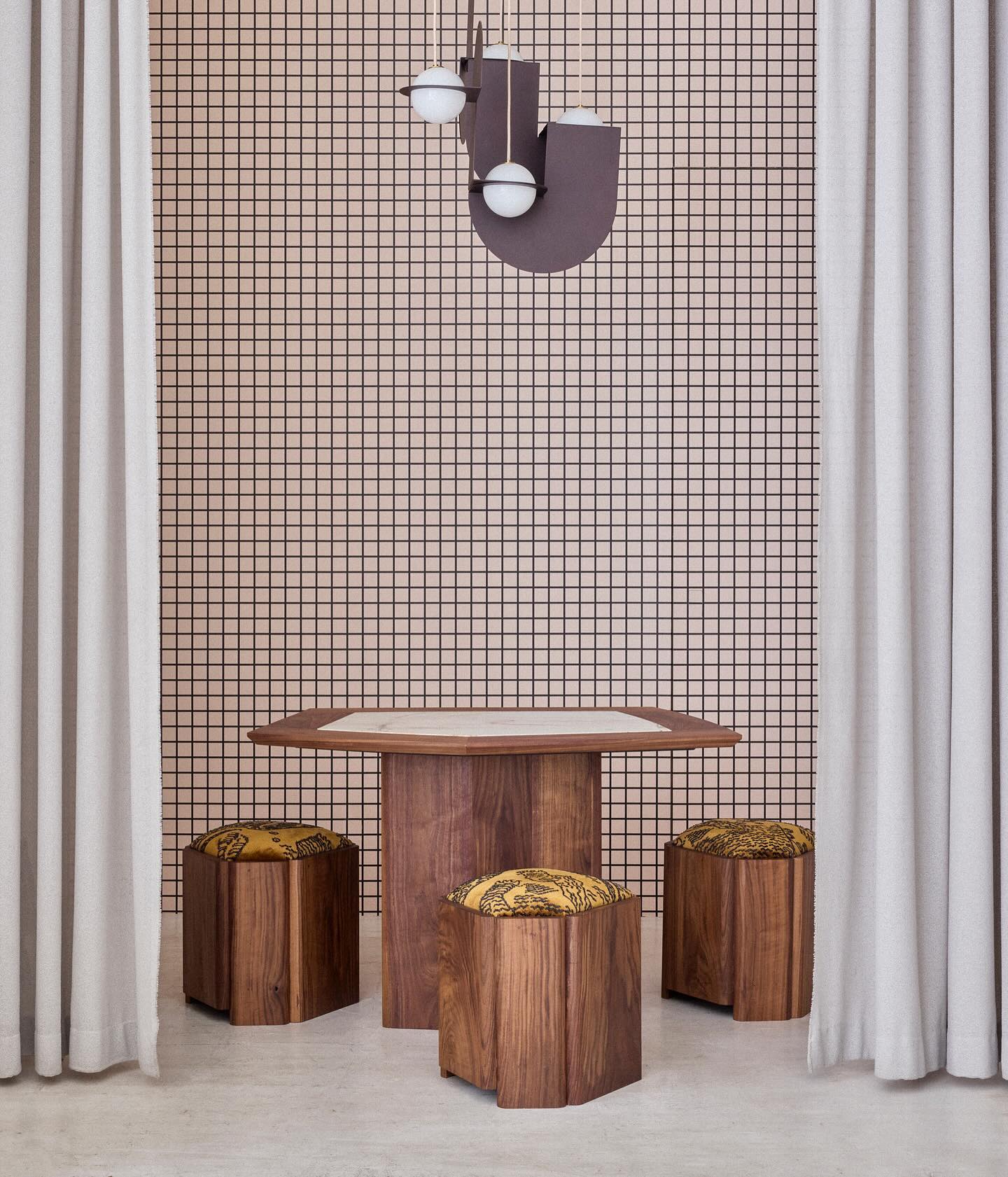 Octagonal walnut coffee table with a natural stone top in a hotel lobby, surrounded by matching upholstered stools