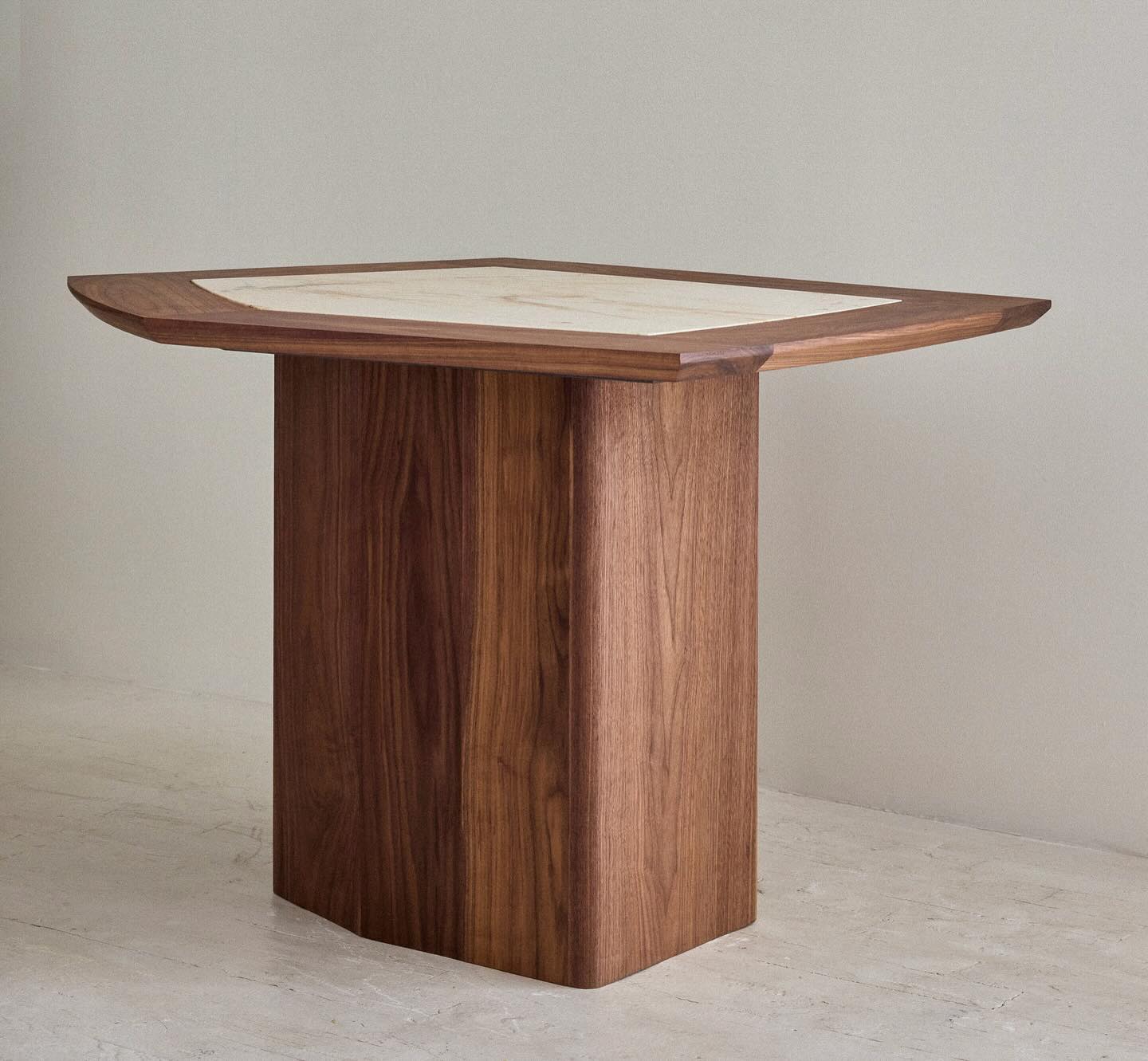 The octagonal walnut coffee table shown on its own in a studio setting, with the stone top inlaid flush