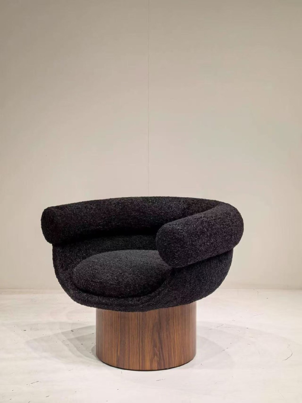 Angled view of the black textured lounge chair showing curved arm and walnut base