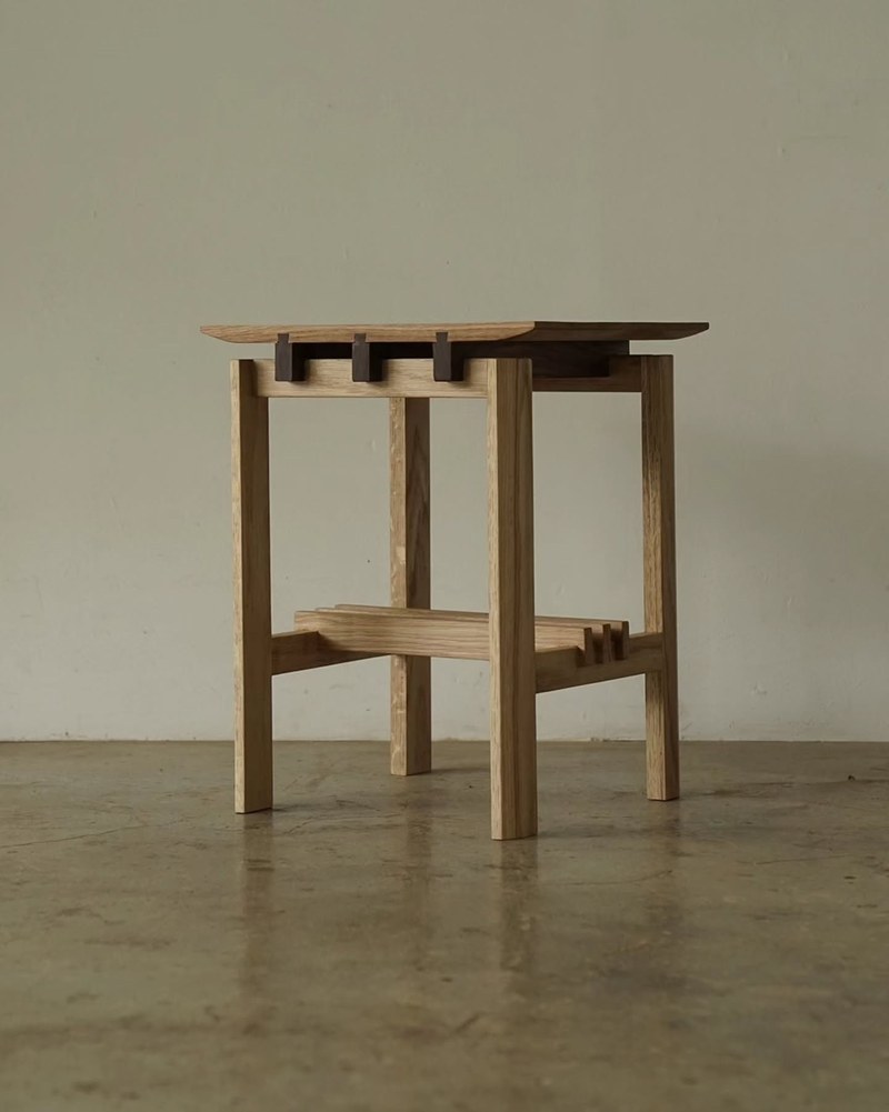 Three-quarter view of a custom wood side table with contrasting dark joinery and an open frame