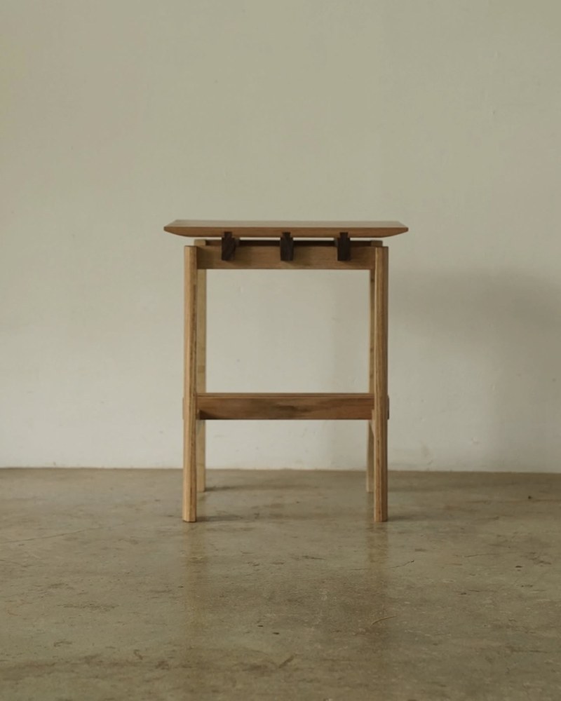Front view of a wood side table with four legs and contrasting joinery details