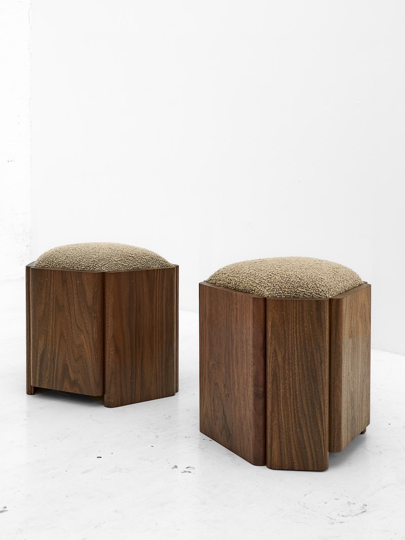 Beige upholstered hotel stool showing vertical wood grain and rounded base edges