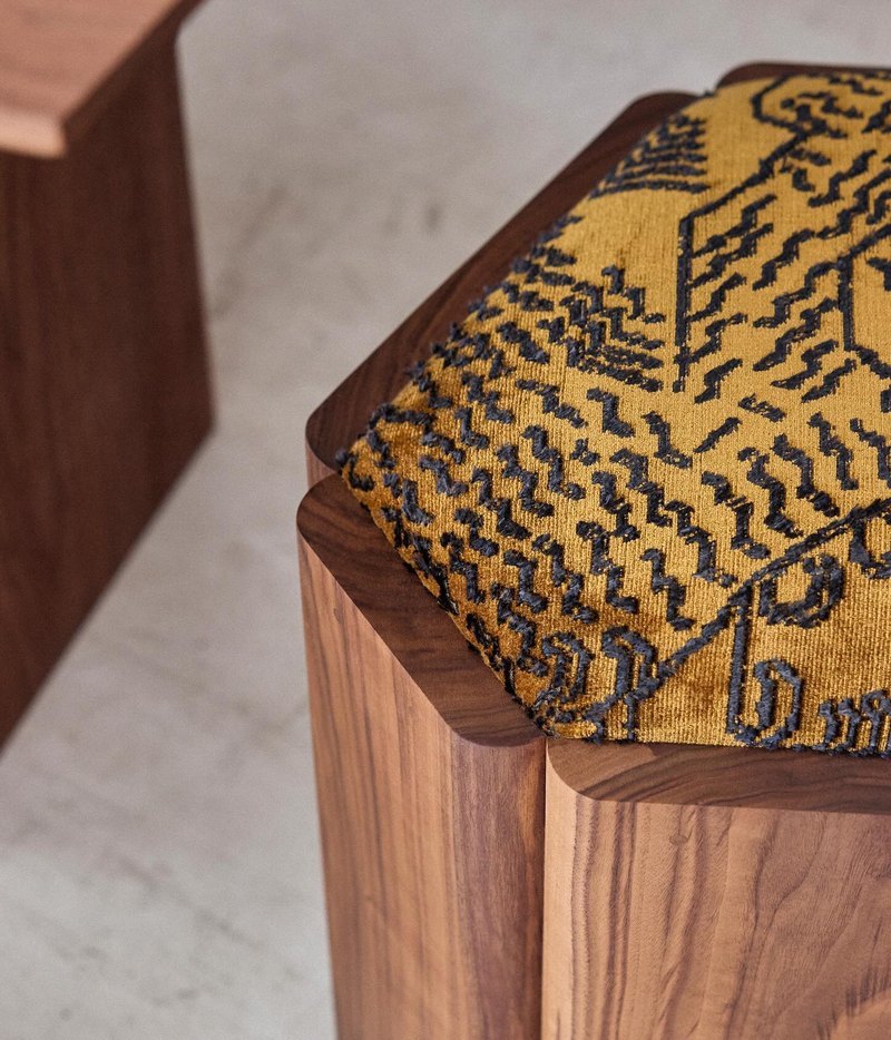 Close view of mustard patterned upholstery within the rounded wood surround