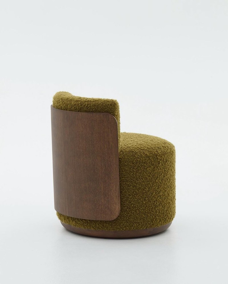 Rear angled view of moss green textured hotel accent chair with a curved wood grain back panel