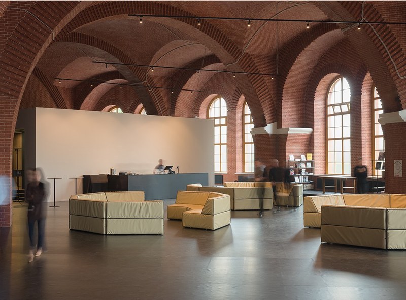 Open hospitality lounge layout with individual and grouped modular sofas in a vaulted interior