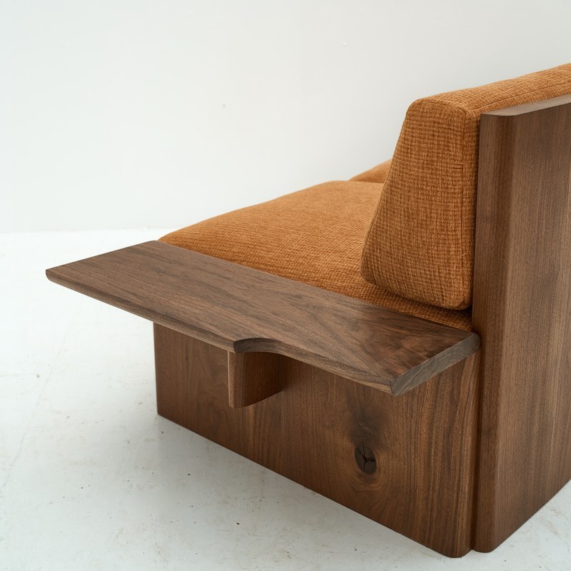Detail of the shaped wooden armrest and vertical wood side panel on a hotel sofa