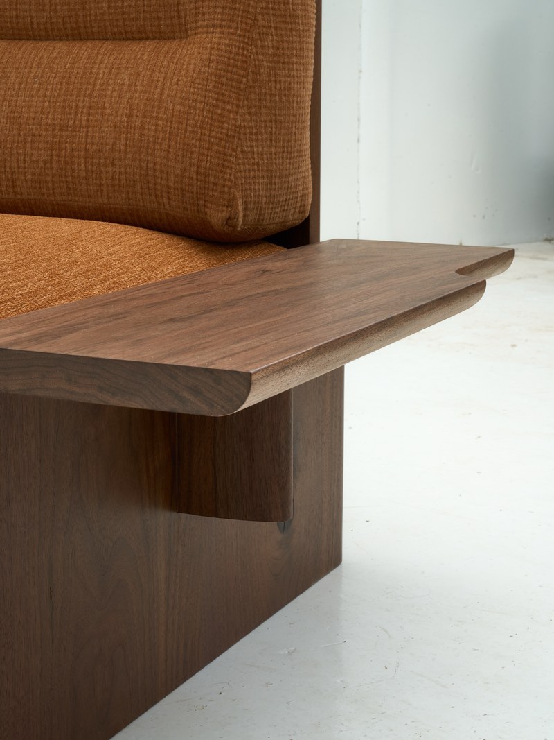 Seat and armrest detail of a hotel sofa with curved wood edge and woven upholstery