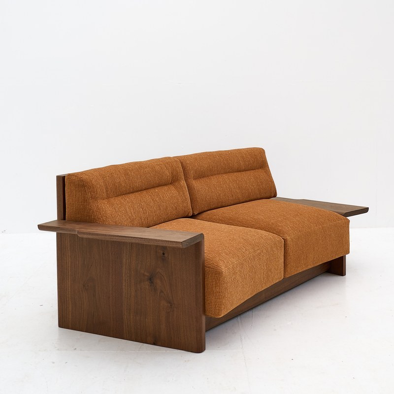 Rear three-quarter view showing the curved wood back panel of a two-seater hotel sofa