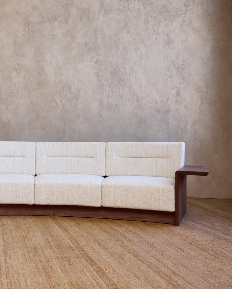 Right wood arm and upholstered seat of a curved hotel suite sofa in ivory fabric