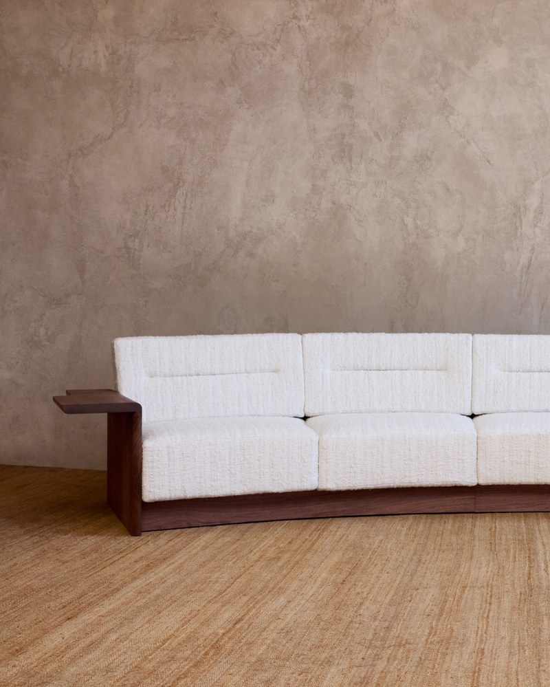 Left wood arm of a hotel suite sofa showing the seat proportions and curved base