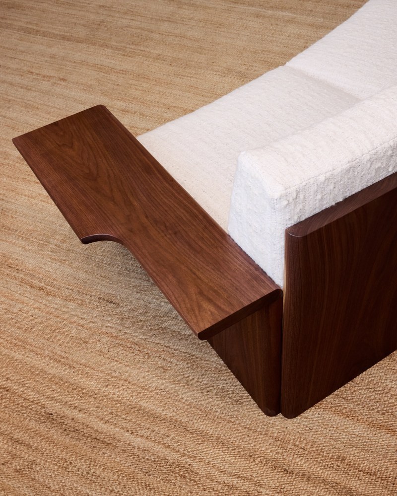 Detail of the offset notch and visible walnut grain on a hotel sofa arm