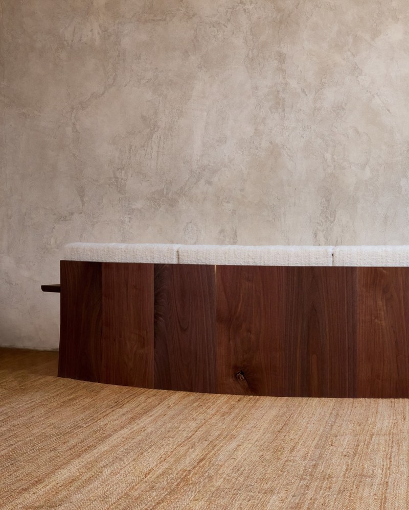 Rear view of a curved hotel sofa showing the wood-grain back panel above the floor