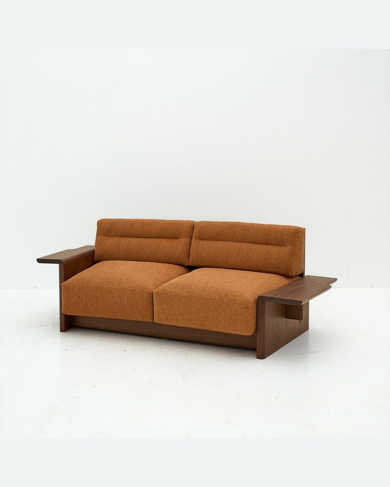 Three-quarter view of a two-seater hotel lounge sofa with wide wooden armrests
